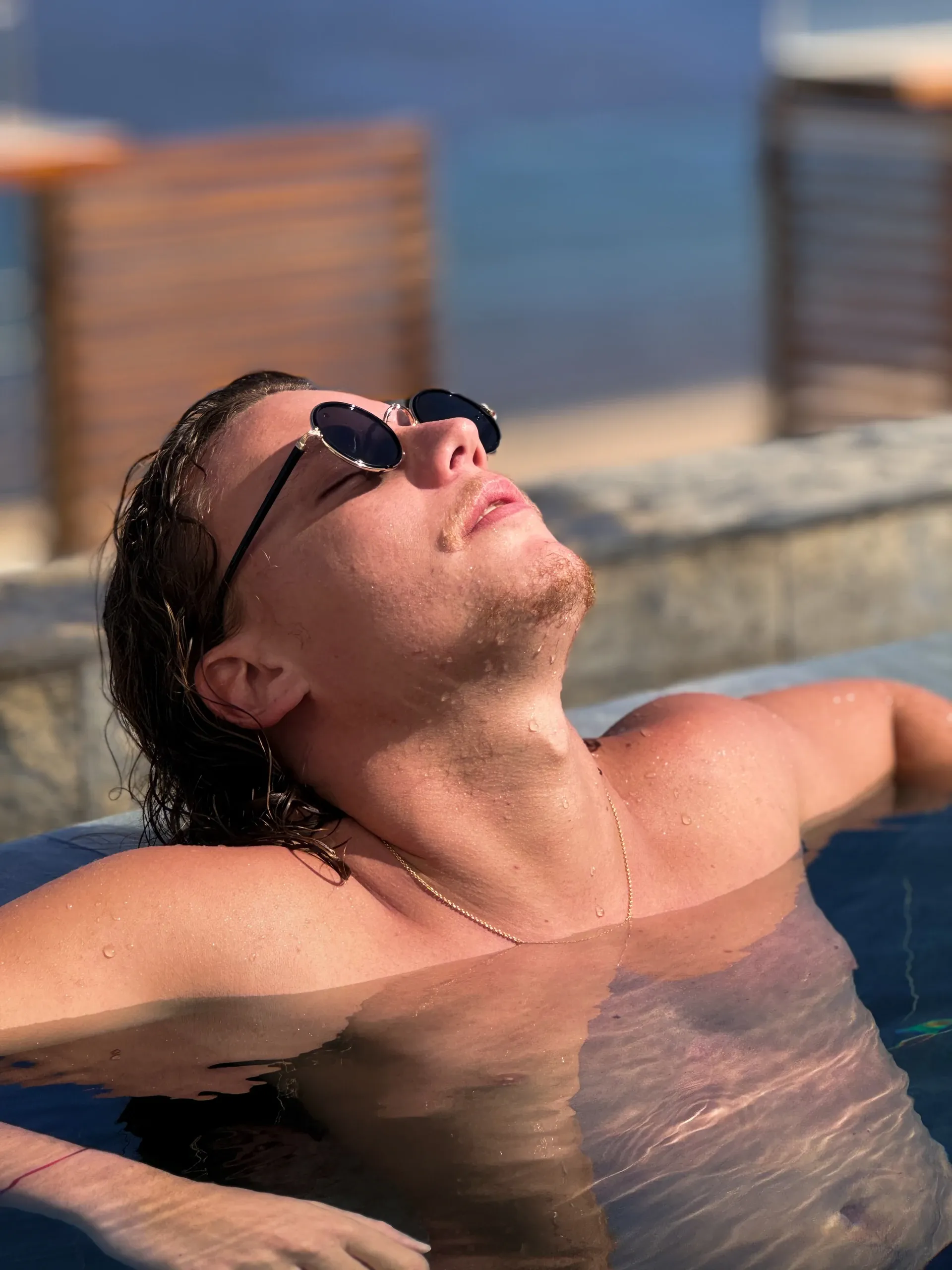 Dono dans l'eau, lunettes de soleil, le visage tendu vers le soleil.