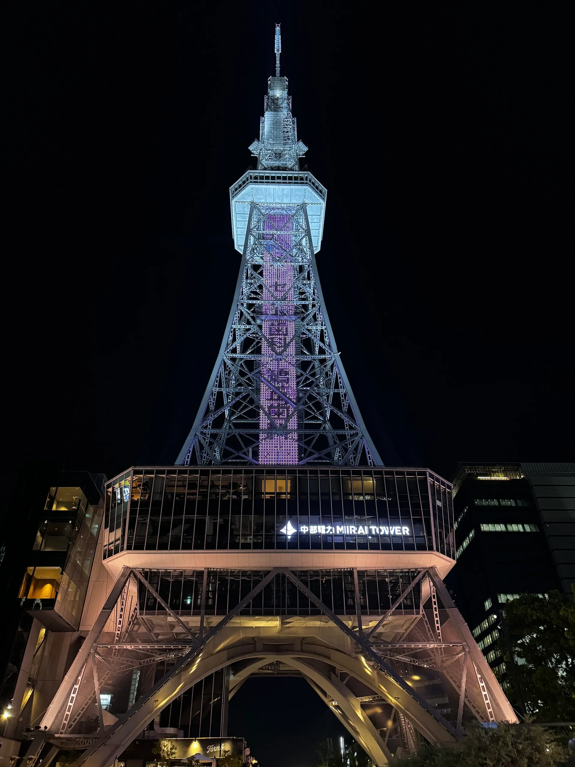 Tour de télévision illuminée de blanc et de bleu, la nuit.